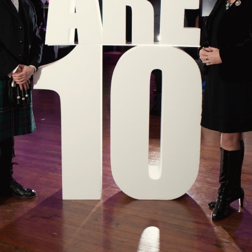 Prop with the number 10 and a man and woman standing on either side of it