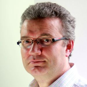 Man with glasses and grey hair looking to camera