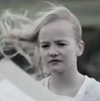 Blonde girl standing outside with hair being blown by the wind