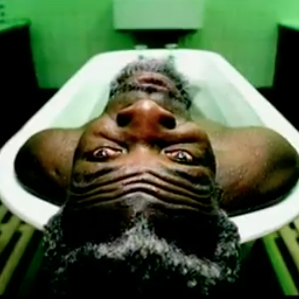 Man in bath tub, laying back looking a the camera upside down