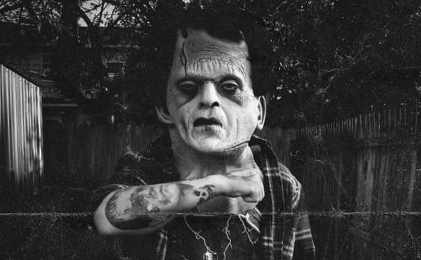 Man with Frankenstein mask on showing his Frankenstein tattoo