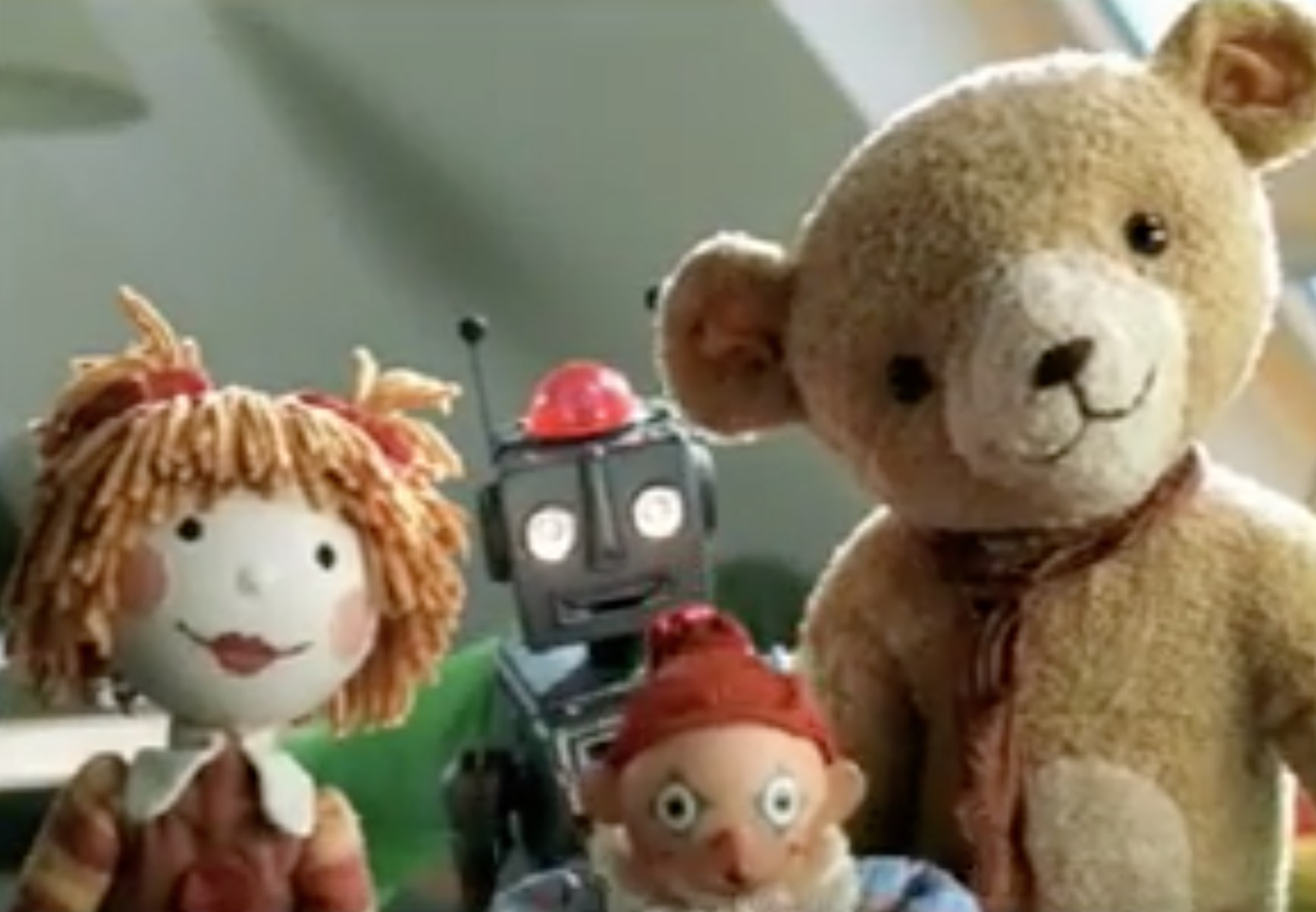 Group of toys facing the camera, a robot, teddy bear, doll and jack in the box