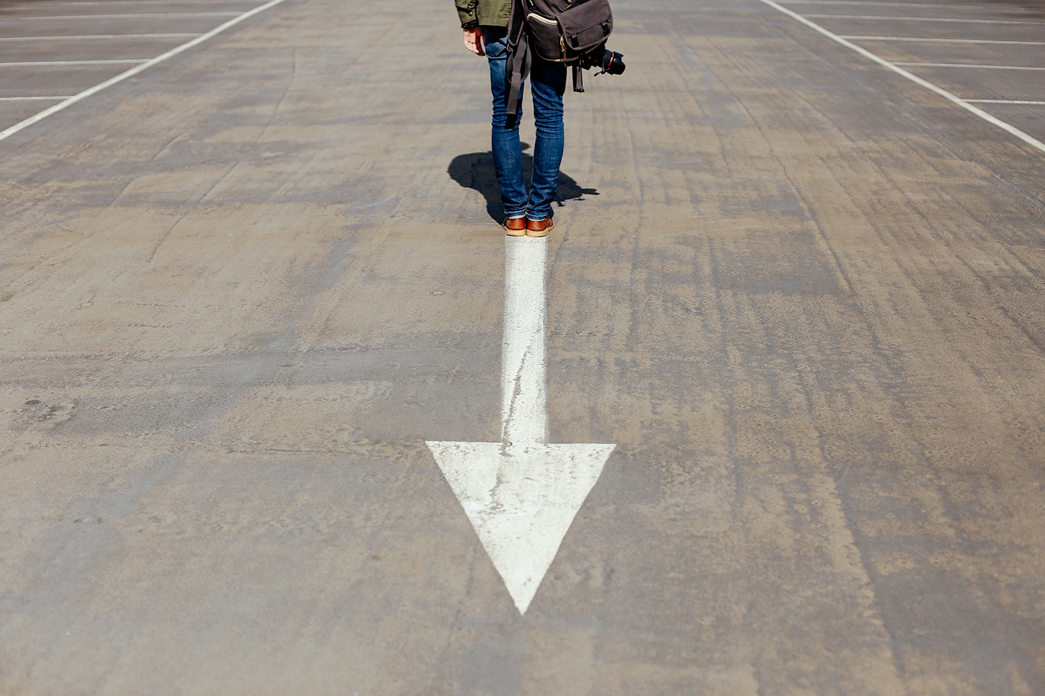 Man standing on road with Arrow on road pointing down while he is looking forward