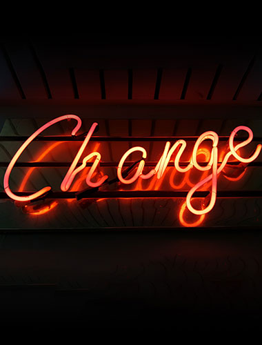 Neon sign lit up with the word written in red "Change"