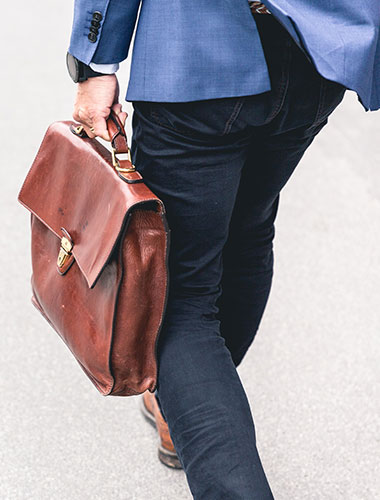 Man with briefcase walking, in a blue jacket and blue jeans