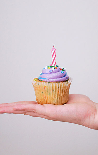 hand holding a cake with a candle in it