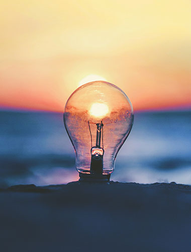 lightbulb in sand with sunset in background