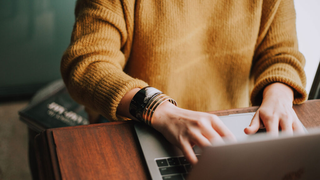 Person in yellow top using a laptop