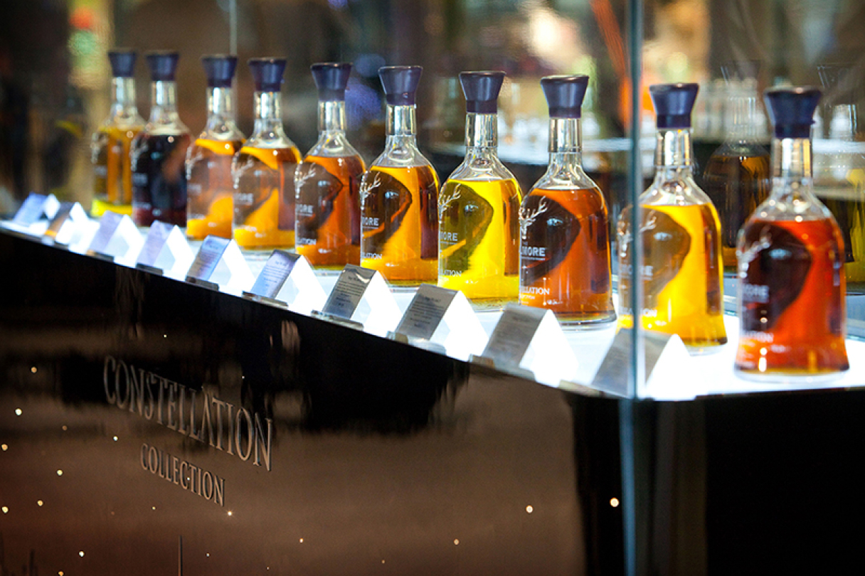 Group of various Dalmore whisky bottles in a glass display cabinet