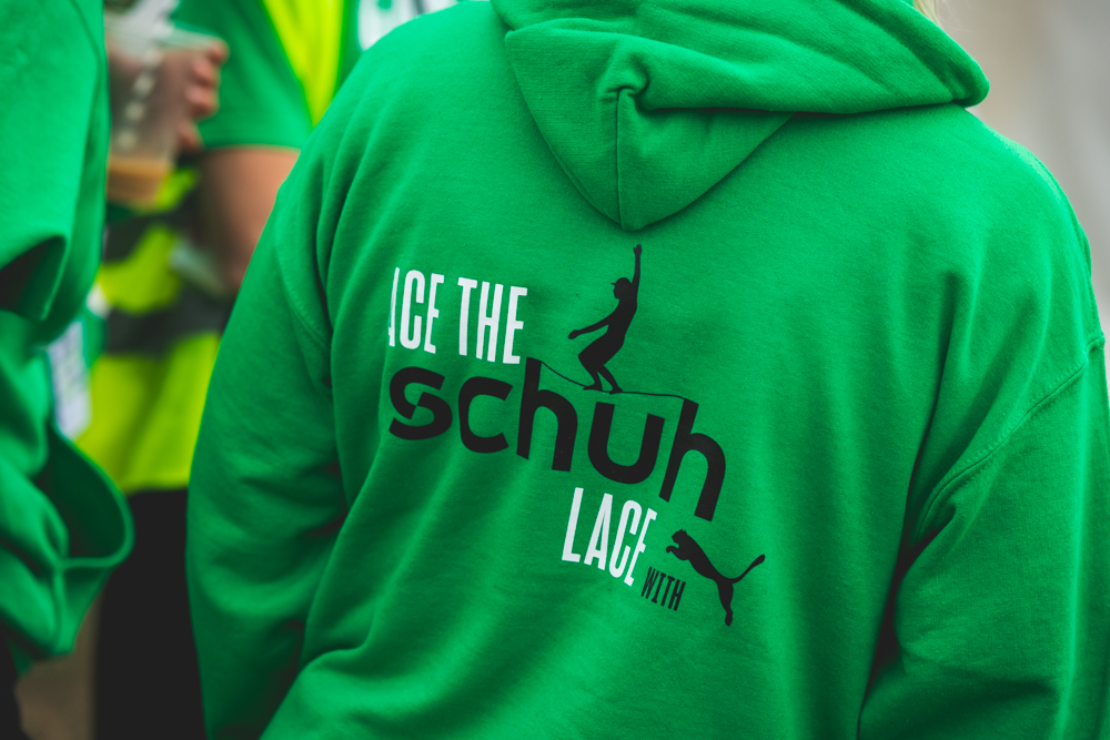 Man wearing green hoodie with Schuh logo