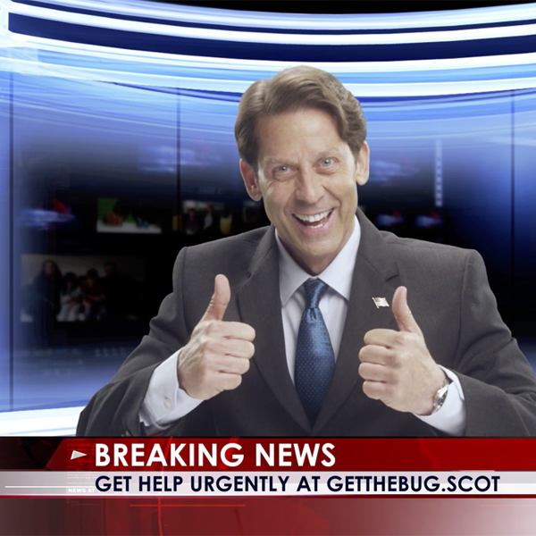 Man at news desk giving two thumbs up and smiling