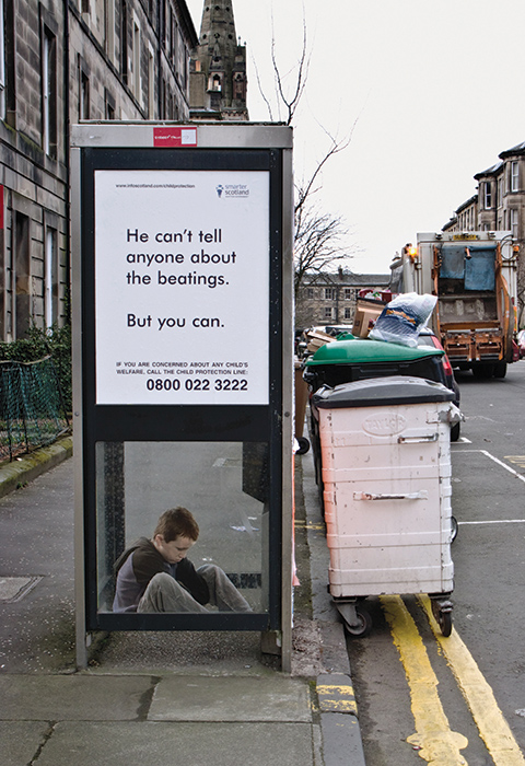 small child huddled in phone box