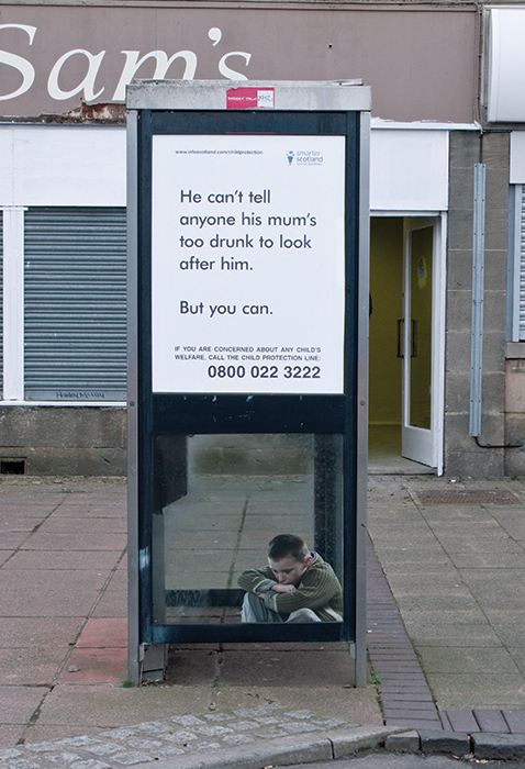 small child huddled in phone box