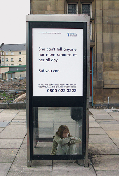 small child huddled in phone box