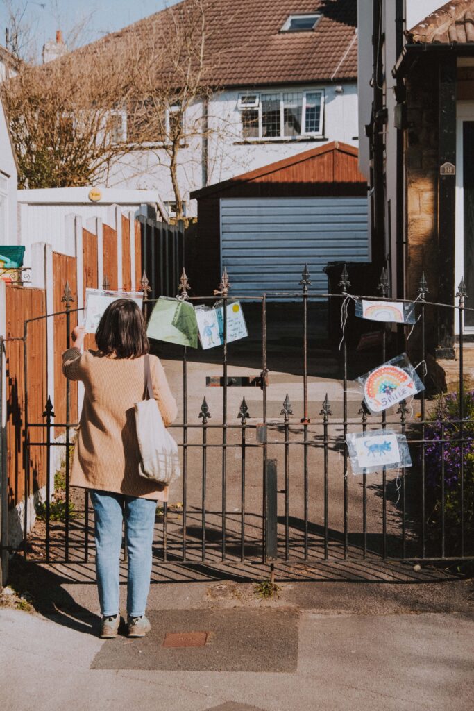 Woman standing in front of gate looking at pictures attached to gate