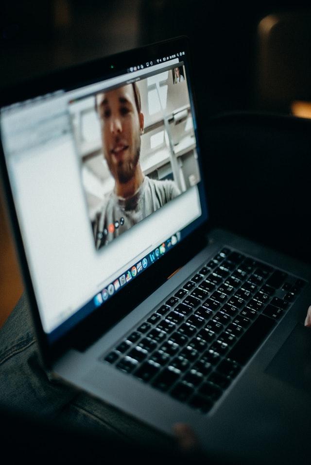 laptop on person's lap, with a man on screen