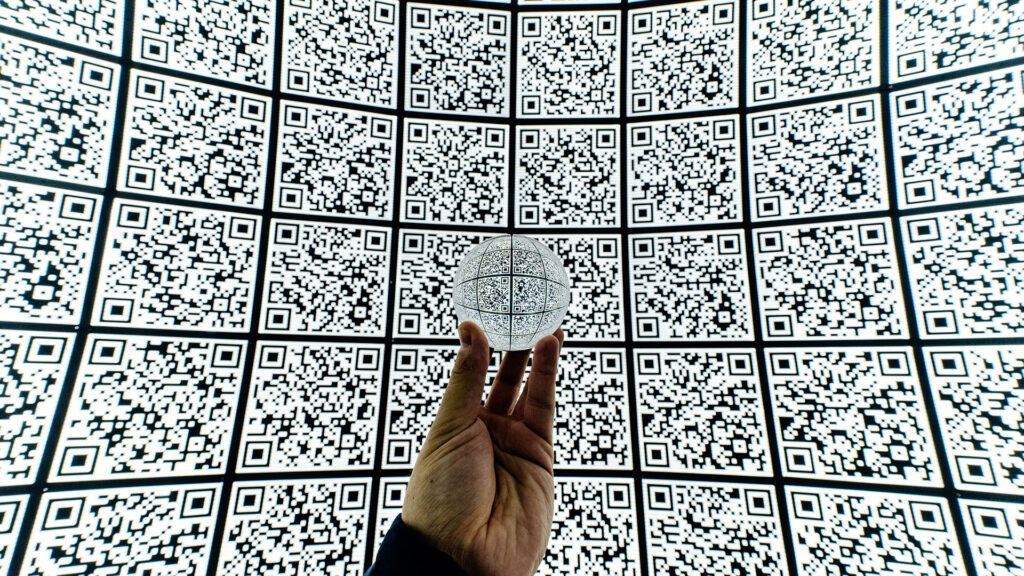 man holding orb with QR codes projected on screens all around the person