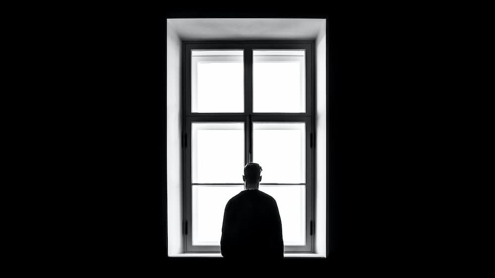 Man looking out of a window in a dark room