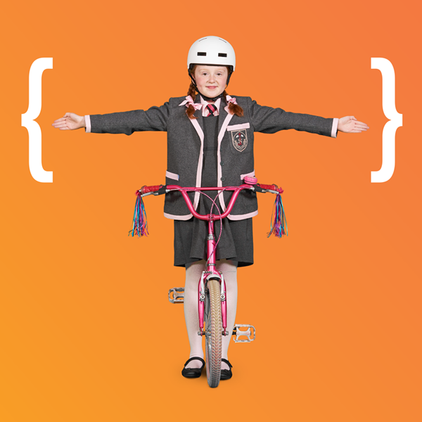 Girl on bike in school uniform with arms stretched out