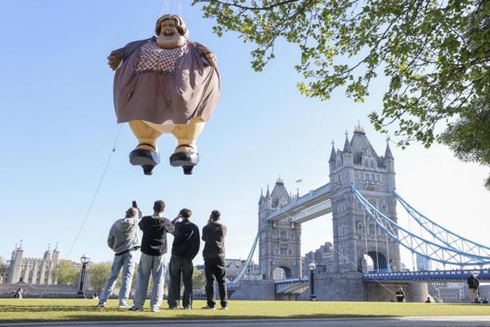 People looking at an inflatable woman in the sky near London Bridge