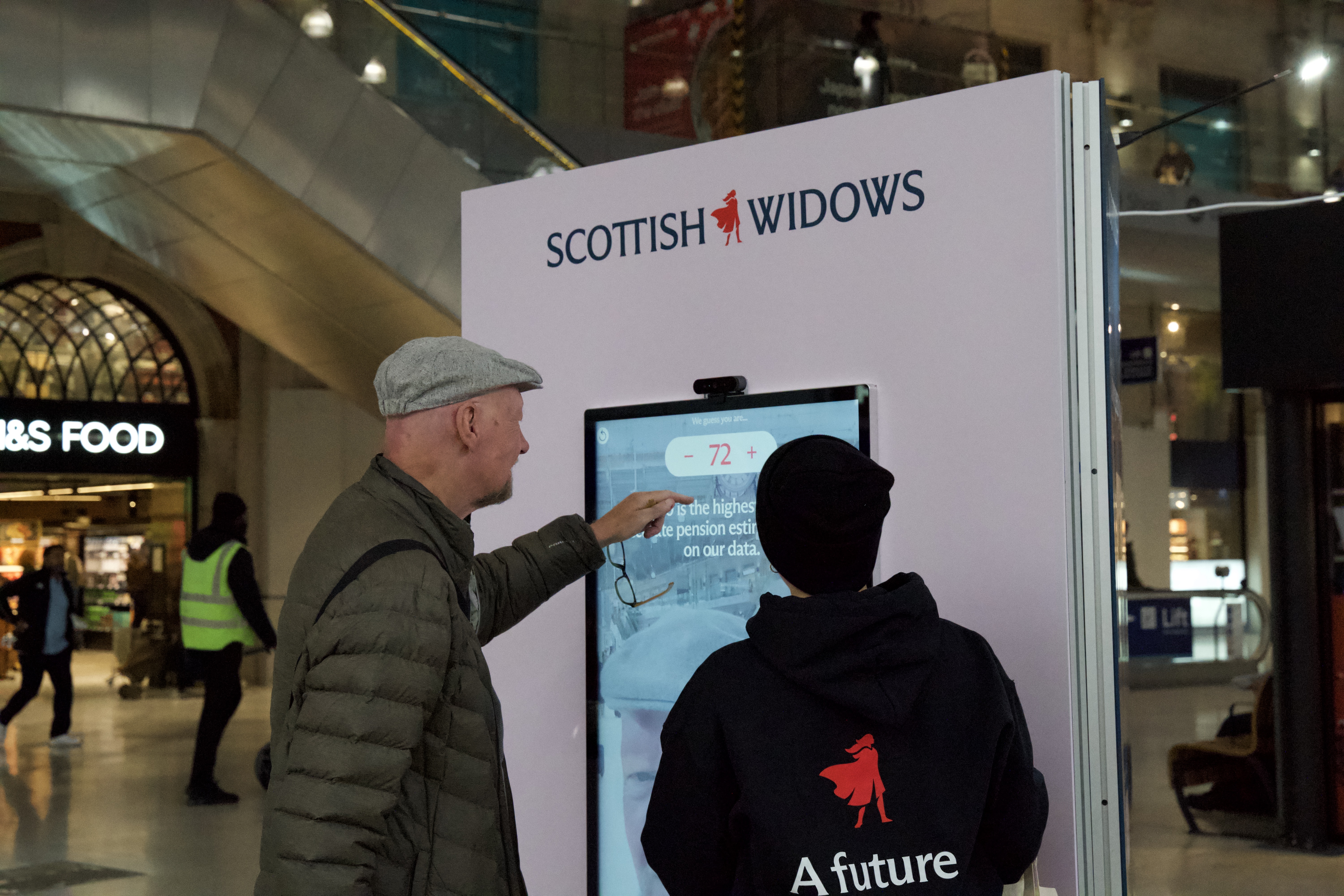 Man using the digital display with the help of a member of the team