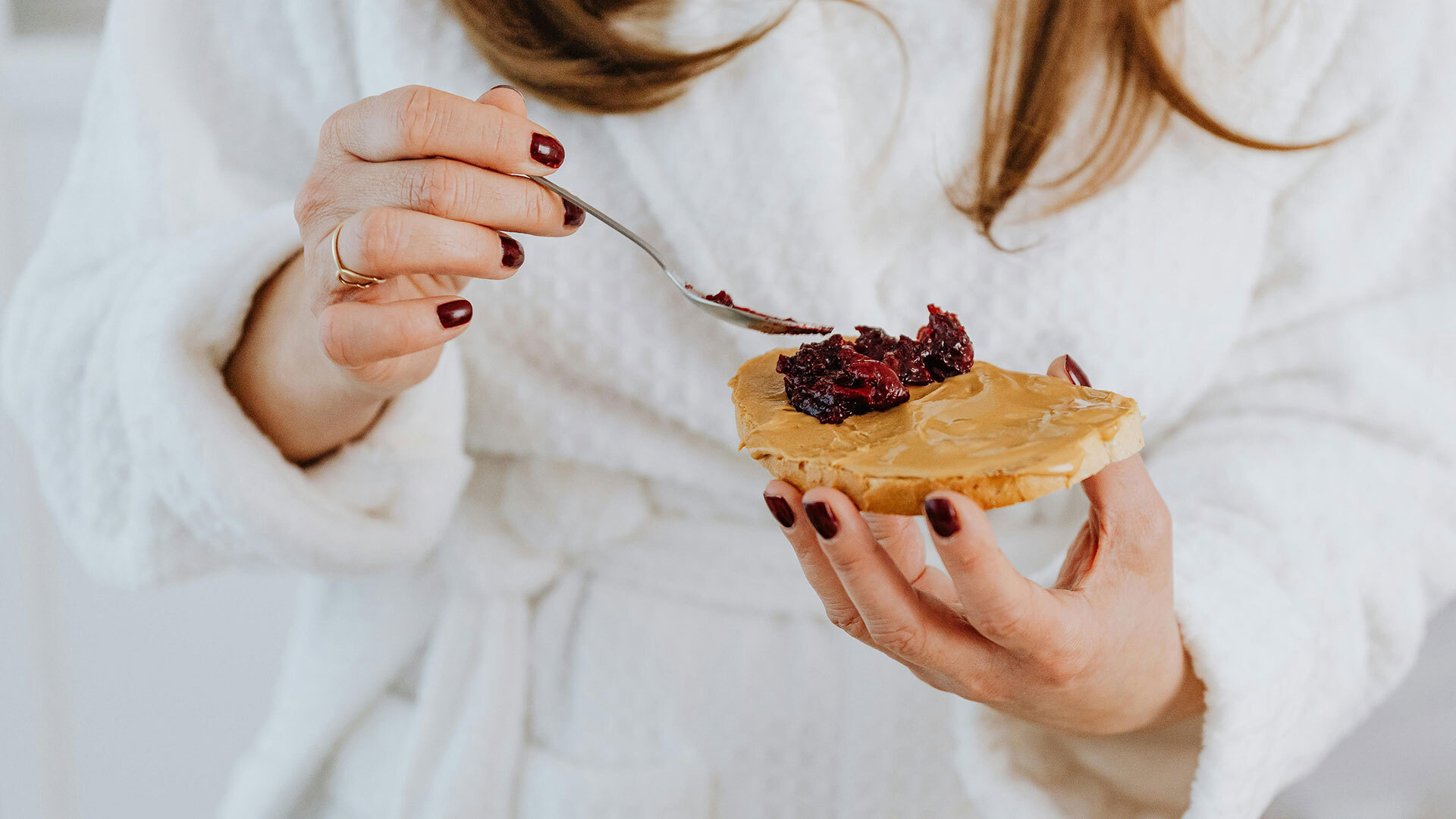 person spreading jam / jelly onto bread with peanut butter