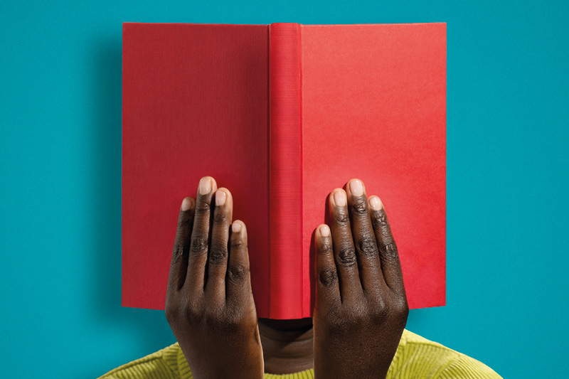 image of a person hiding behind a book